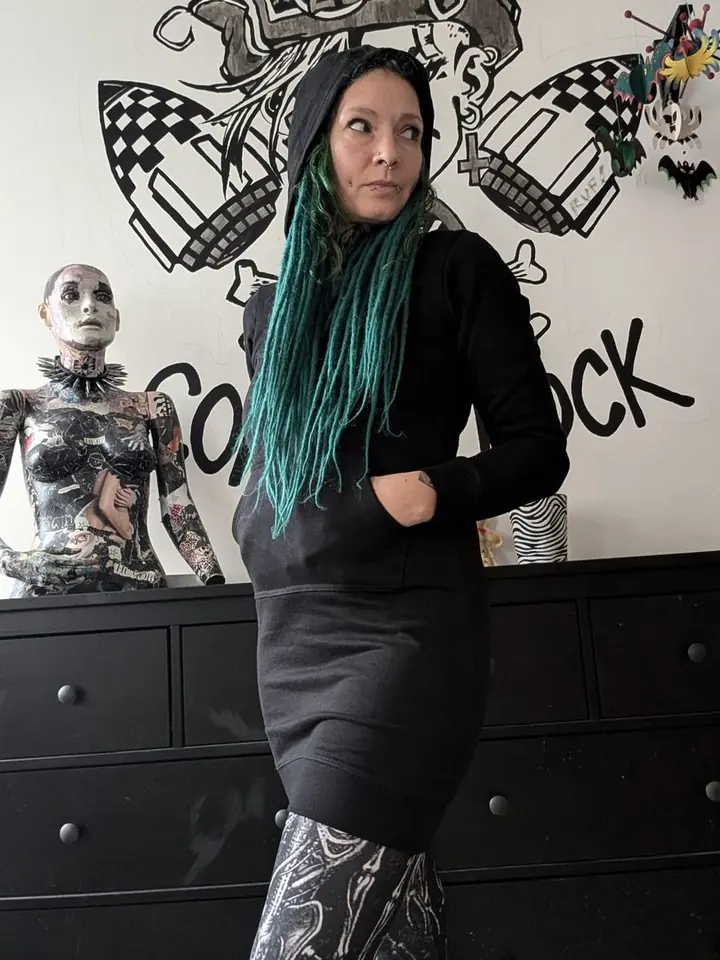 Frau mit grünen Haaren im schwarzen Hoodie-Kleid